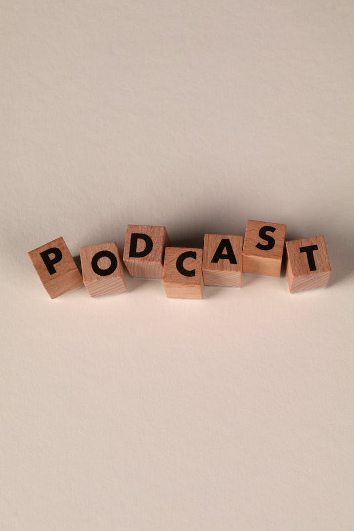 Wooden letter blocks arranged to spell Podcast on a smooth beige background.